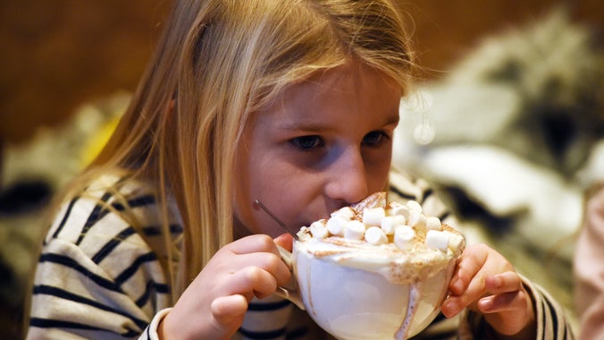Girl sipping a large cup of hot chocolate with marshmallows on the top